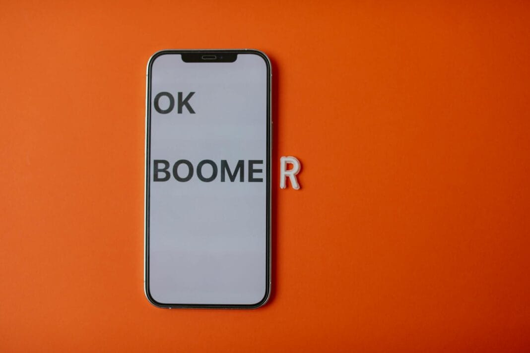 Smartfon z napisem OK Boomer na pomarańczowym tle