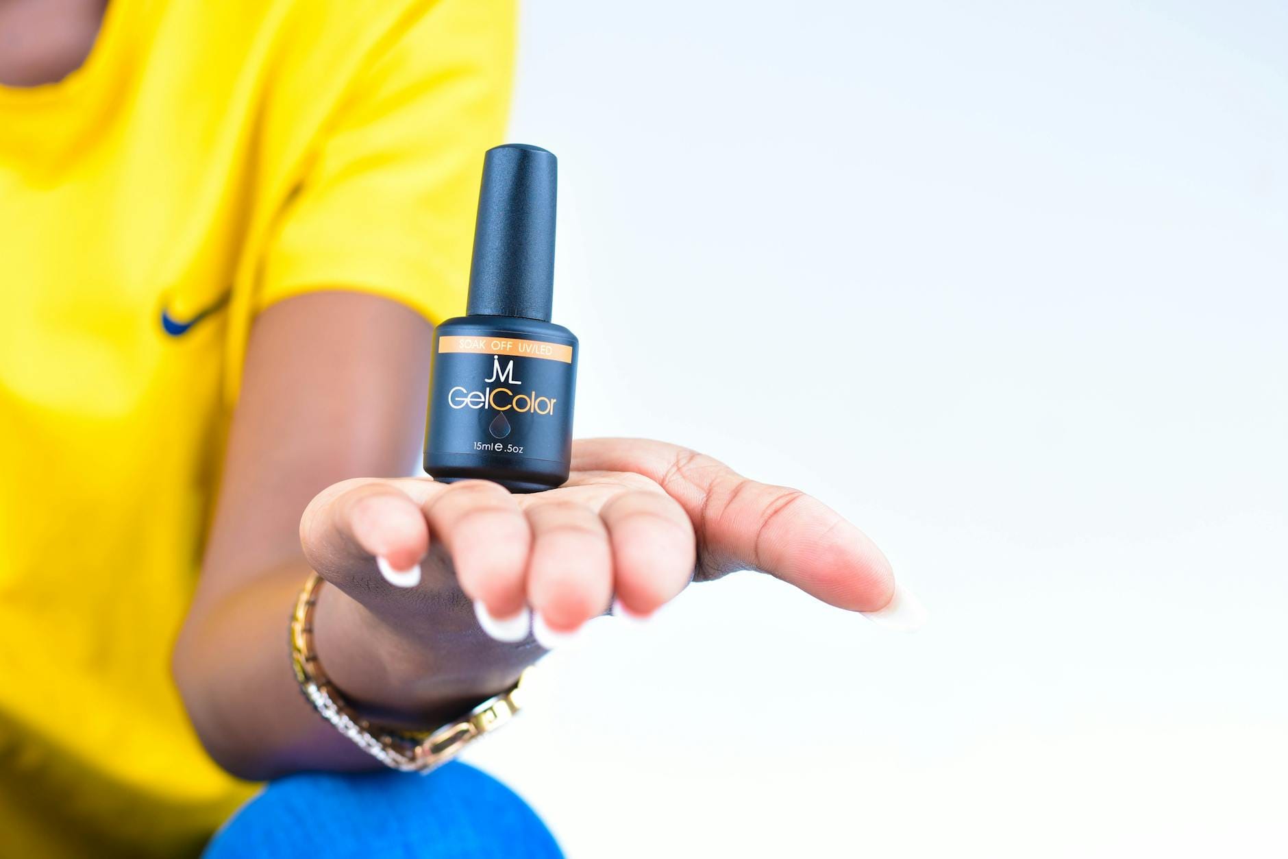 Dłoń z buteleczką lakieru żelowego w zbliżeniu