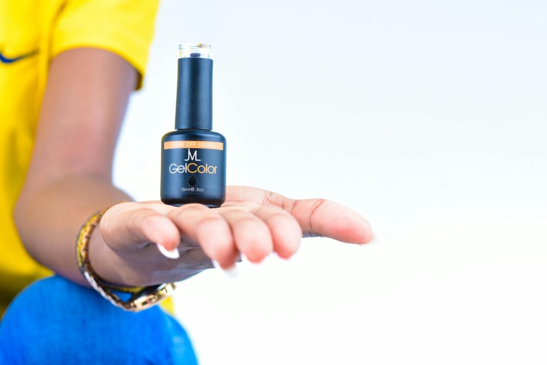 Dłoń kobiety trzymająca buteleczkę lakieru do manicure żelowego