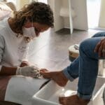 Kosmetyczka wykonuje pedicure stóp klientki w salonie