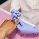 Manicurzystka opracowuje skórki klientki w salonie kosmetycznym