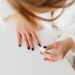 Kobieta w białym szlafroku maluje paznokcie w domu podczas relaksu