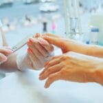 Manicurzystka piłuje paznokcie klientki w salonie manicure