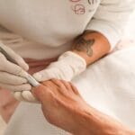Profesjonalna stylistka wykonuje manicure regenerujący paznokcie w salonie