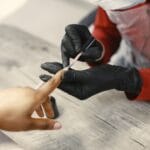 Stylistka nakłada lakier na paznokcie klientki w salonie manicure