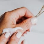 Dłonie nakładające krem z eleganckim manicure i suszonymi kwiatami