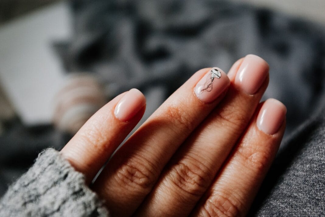 Dłonie kobiety w ciepłym swetrze z manicure żelowym i zdobieniami Dłonie kobiety w ciepłym swetrze z manicure żelowym i zdobieniami
